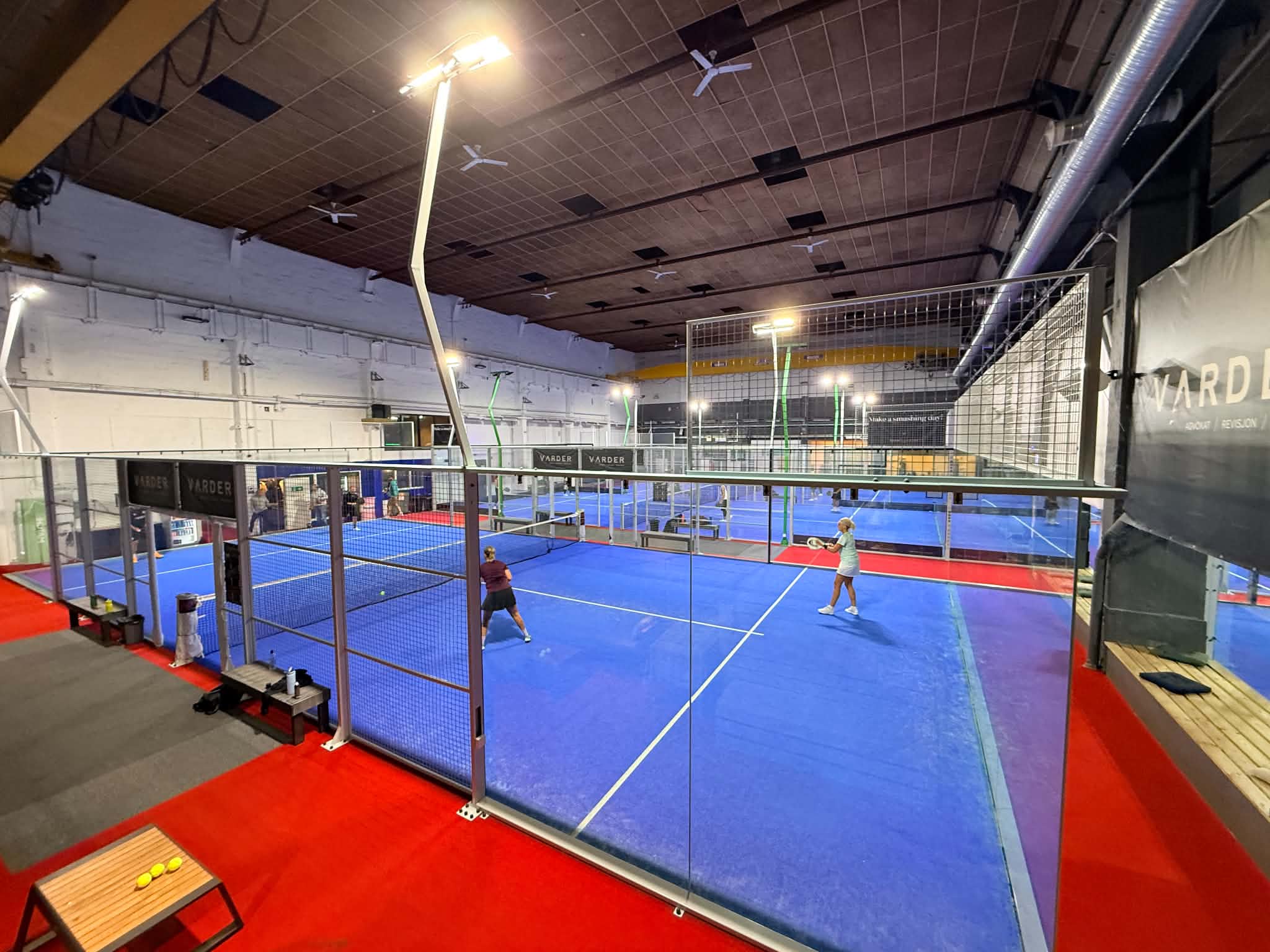 To spillere midt i en ballveksling på en av banene i Moss Padelsenter, med flere baner i bakgrunnen