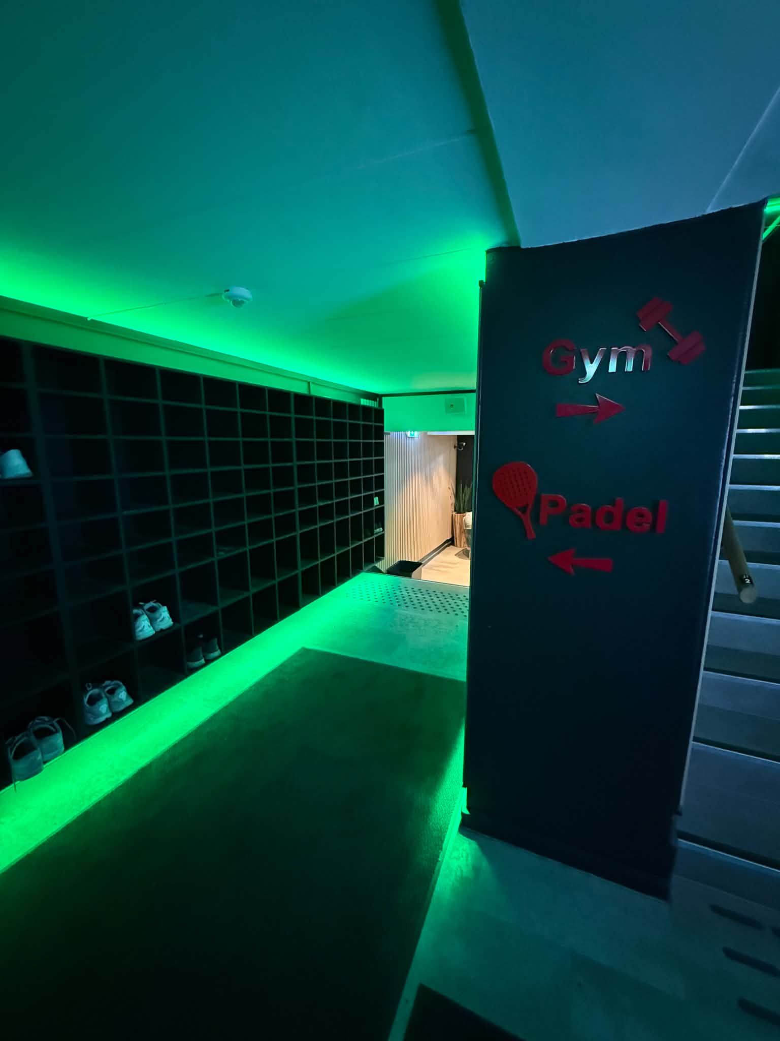 Inngangspartiet i Moss Padelsenter, med skohyller og skilt som viser vei til gym og padel
